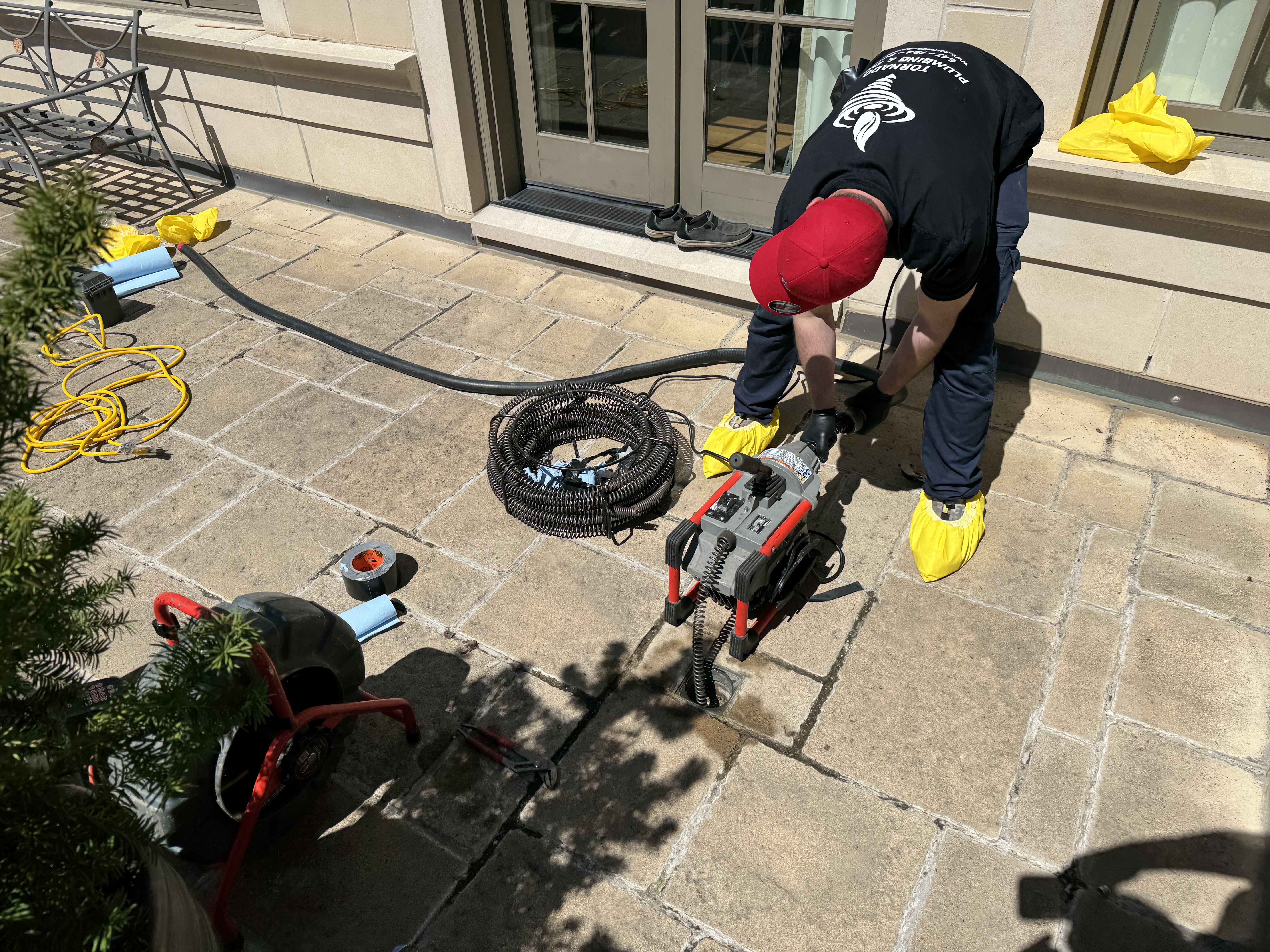 Drain access and service equipment set up on a stone terrace during plumbing work